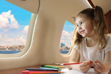 Image of Cute little girl looking out of window at table in airplane during flight