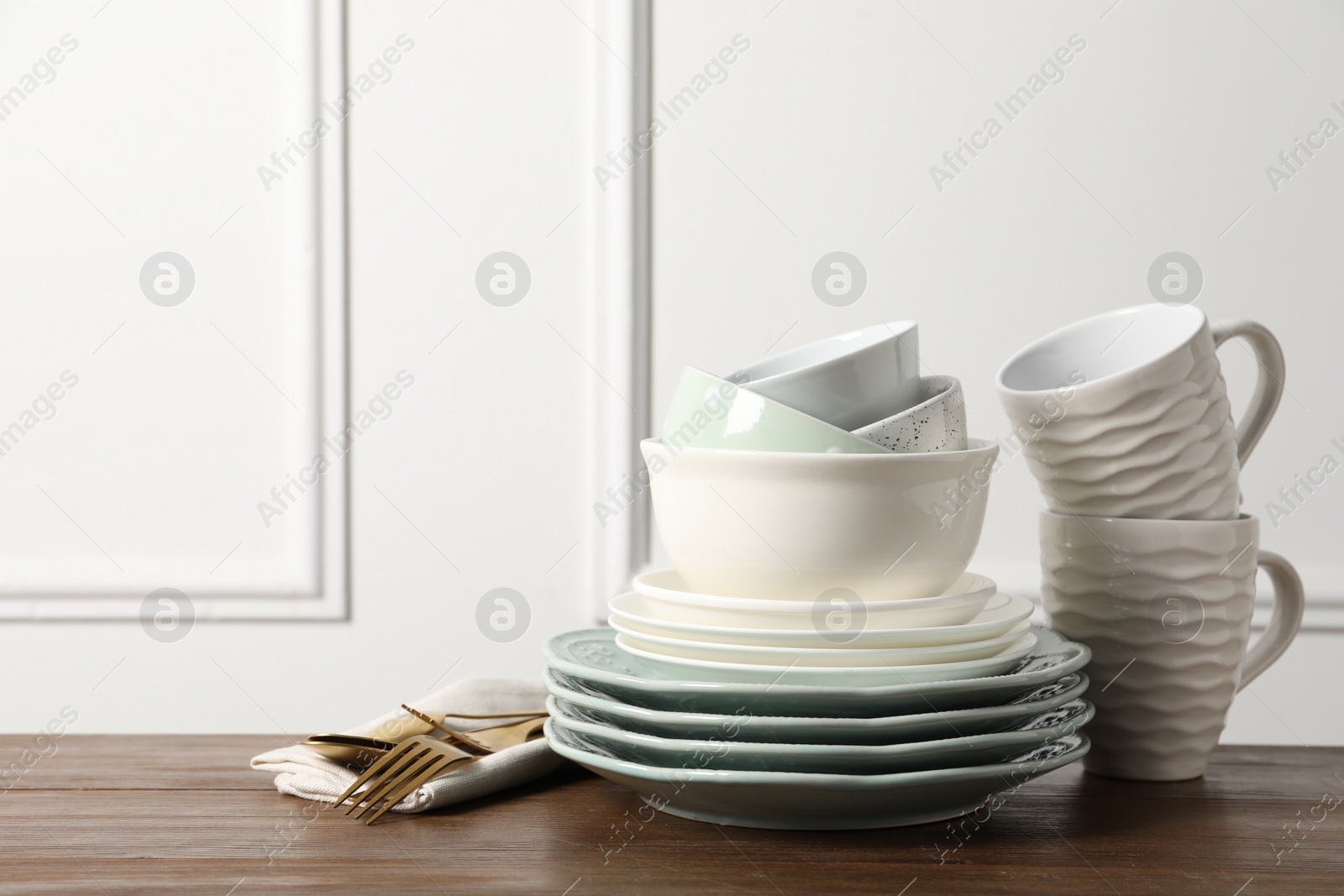 Photo of Beautiful ceramic dishware, cups and cutlery on wooden table, space for text