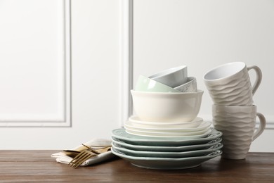 Photo of Beautiful ceramic dishware, cups and cutlery on wooden table, space for text