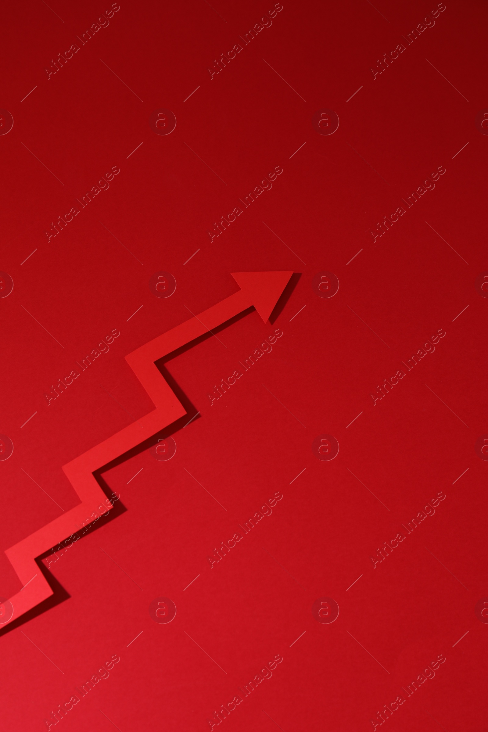 Photo of One zigzag paper arrow on red background, above view. Space for text