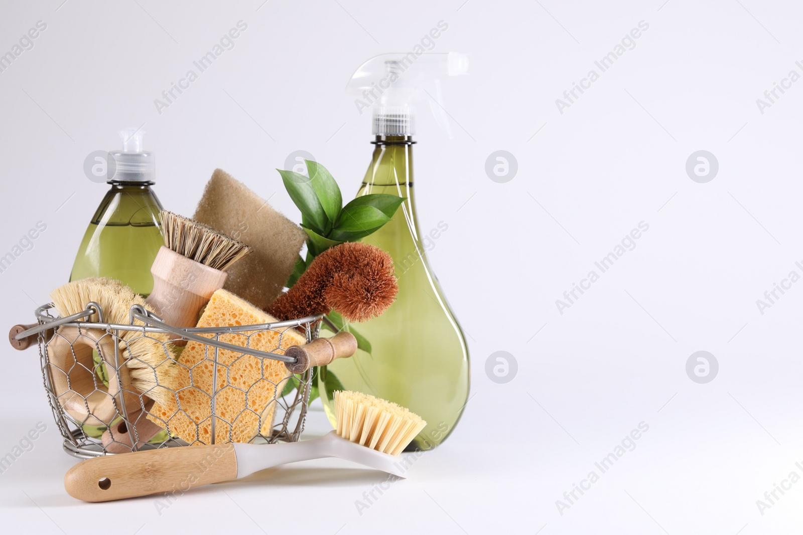 Photo of Set of different cleaning supplies in basket on white background