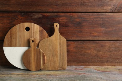 Photo of Set of different cutting boards on table near wooden wall, space for text