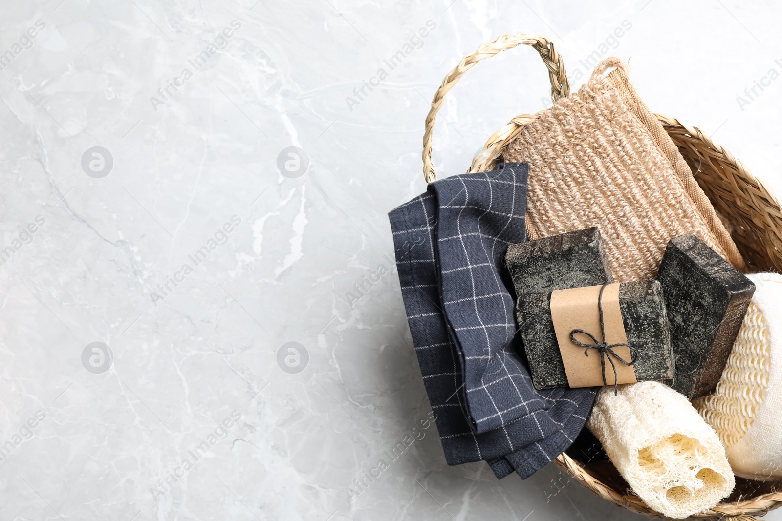 Photo of Natural tar soap in wicker basket on light grey table, top view. Space for text