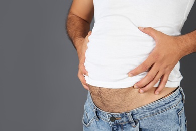 Overweight man on gray background, closeup view