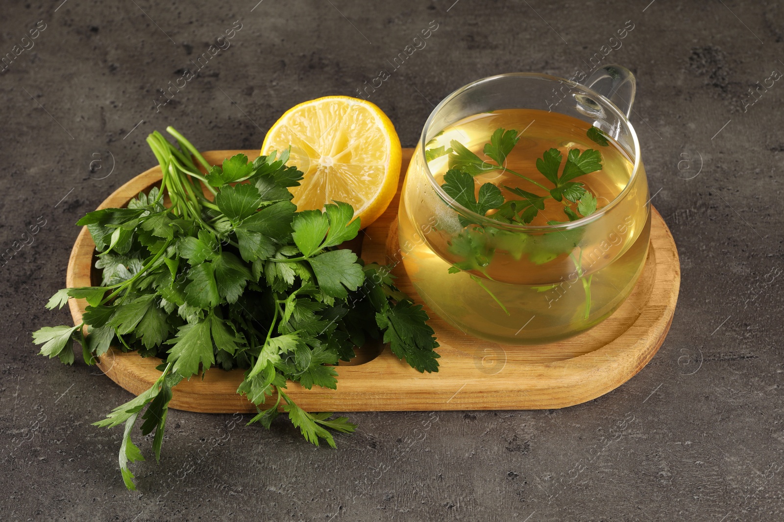 Photo of Aromatic herbal tea, fresh parsley and lemon on grey table