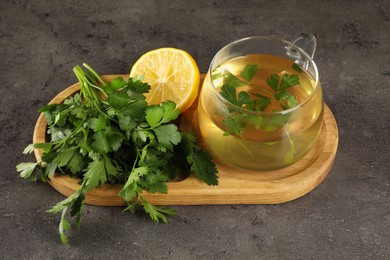 Aromatic herbal tea, fresh parsley and lemon on grey table