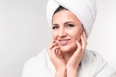 Photo of Beautiful woman with clean skin touching her face on light background