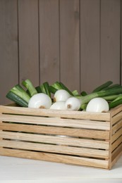 Photo of Crate with green spring onions on white wooden table, space for text