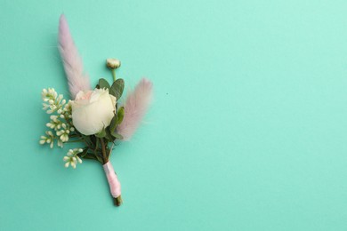 Photo of Small stylish boutonniere on turquoise background, top view. Space for text