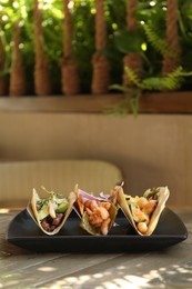 Delicious tacos with shrimps and vegetables on table