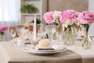 Stylish table setting with beautiful peonies and burning candles indoors