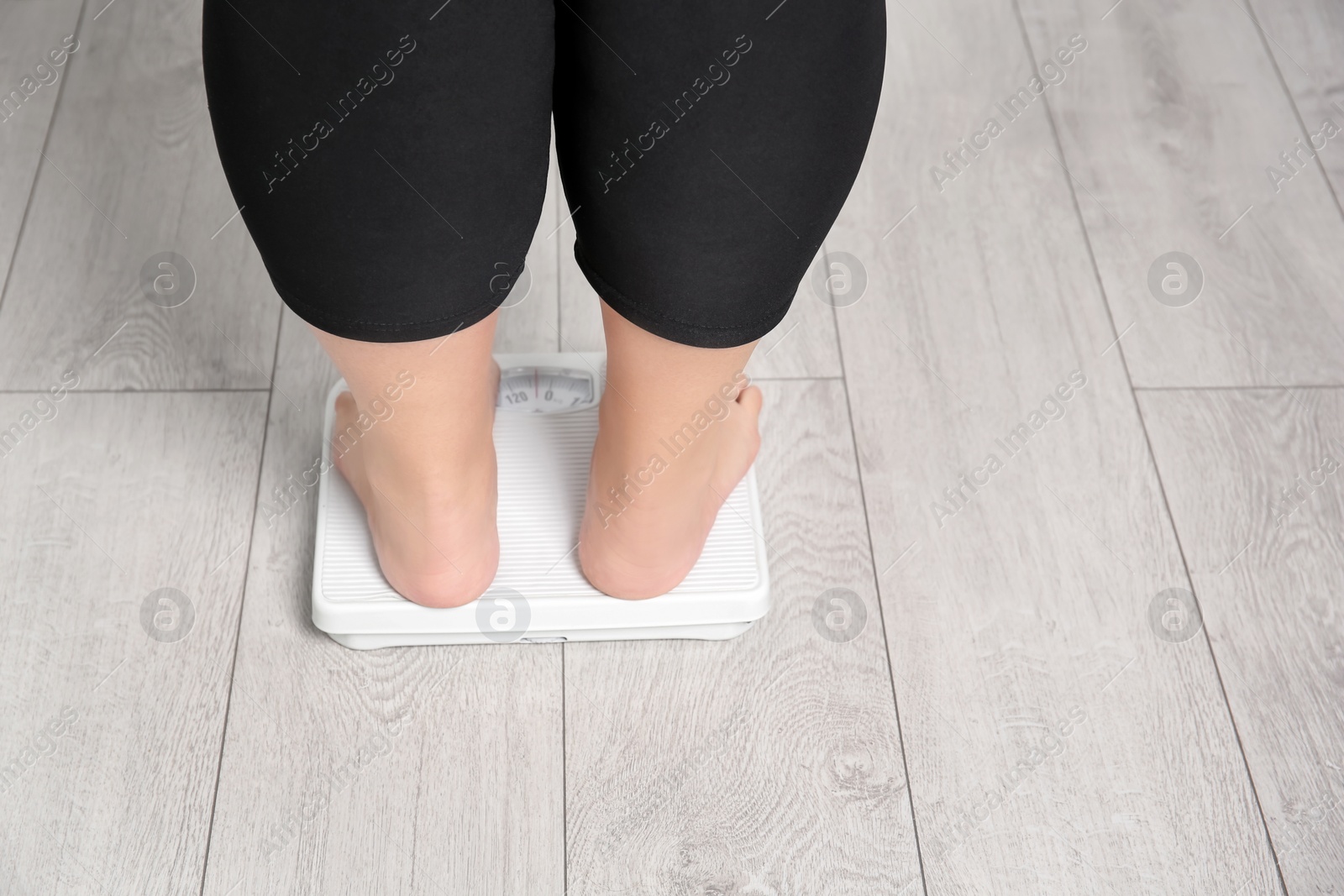 Photo of Overweight woman using scales indoors