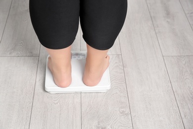 Photo of Overweight woman using scales indoors