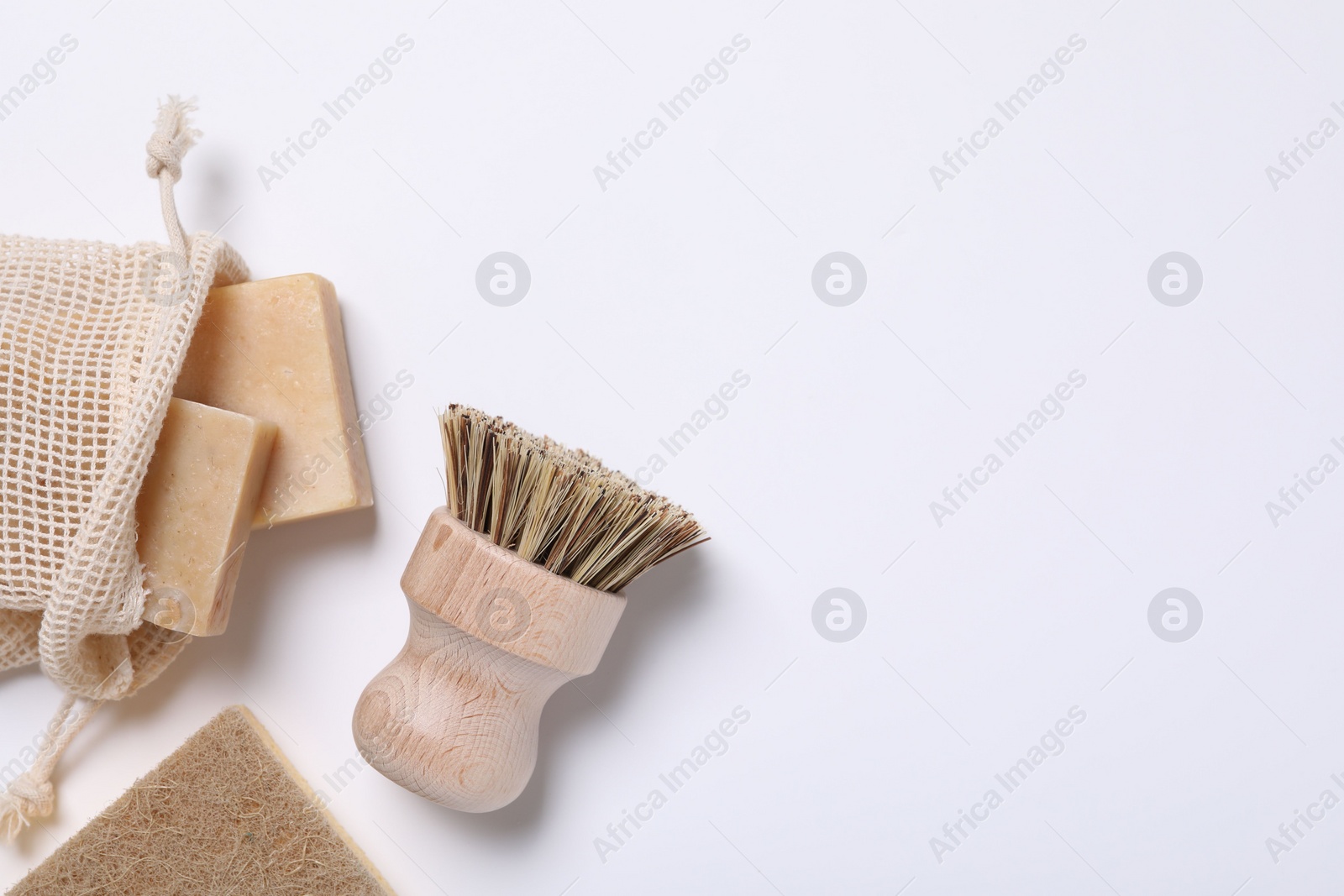 Photo of Cleaning brush, sponge and soap bars on white background, flat lay. Space for text