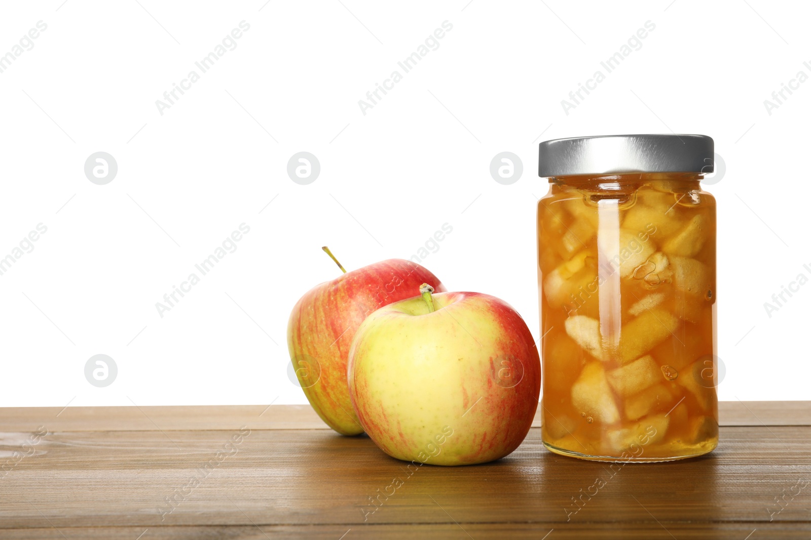 Photo of Tasty apple jam in glass jar and fresh fruits on wooden table against white background, space for text