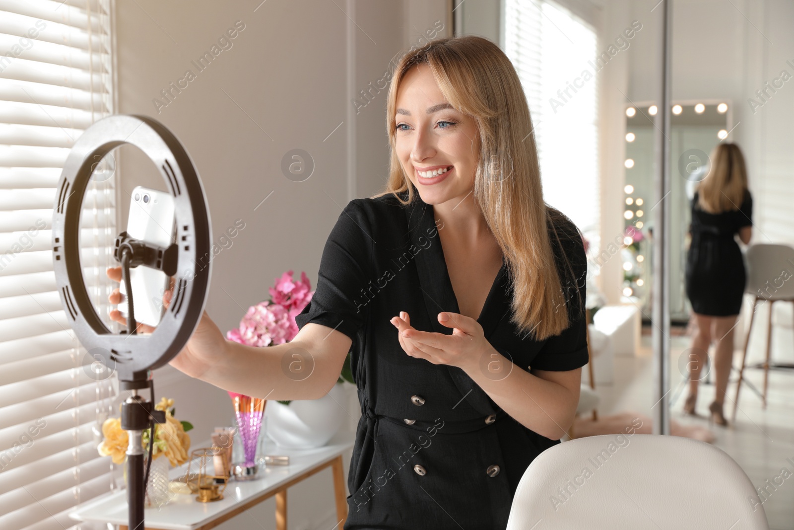 Photo of Blogger recording video in dressing room at home. Using ring lamp and smartphone