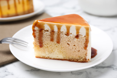 Photo of Slice of delicious cake with caramel sauce on white marble table