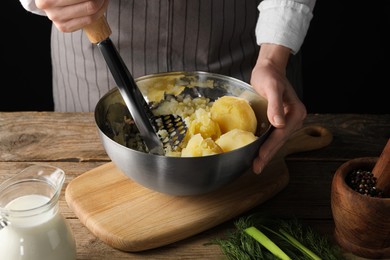 Woman making mashed potato at wooden table, closeup