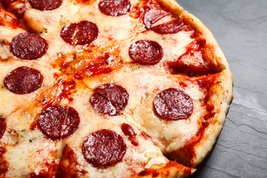 Photo of Hot delicious pepperoni pizza on dark table, closeup