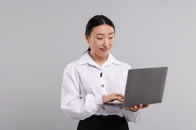 Photo of Portrait of beautiful businesswoman with laptop on grey background