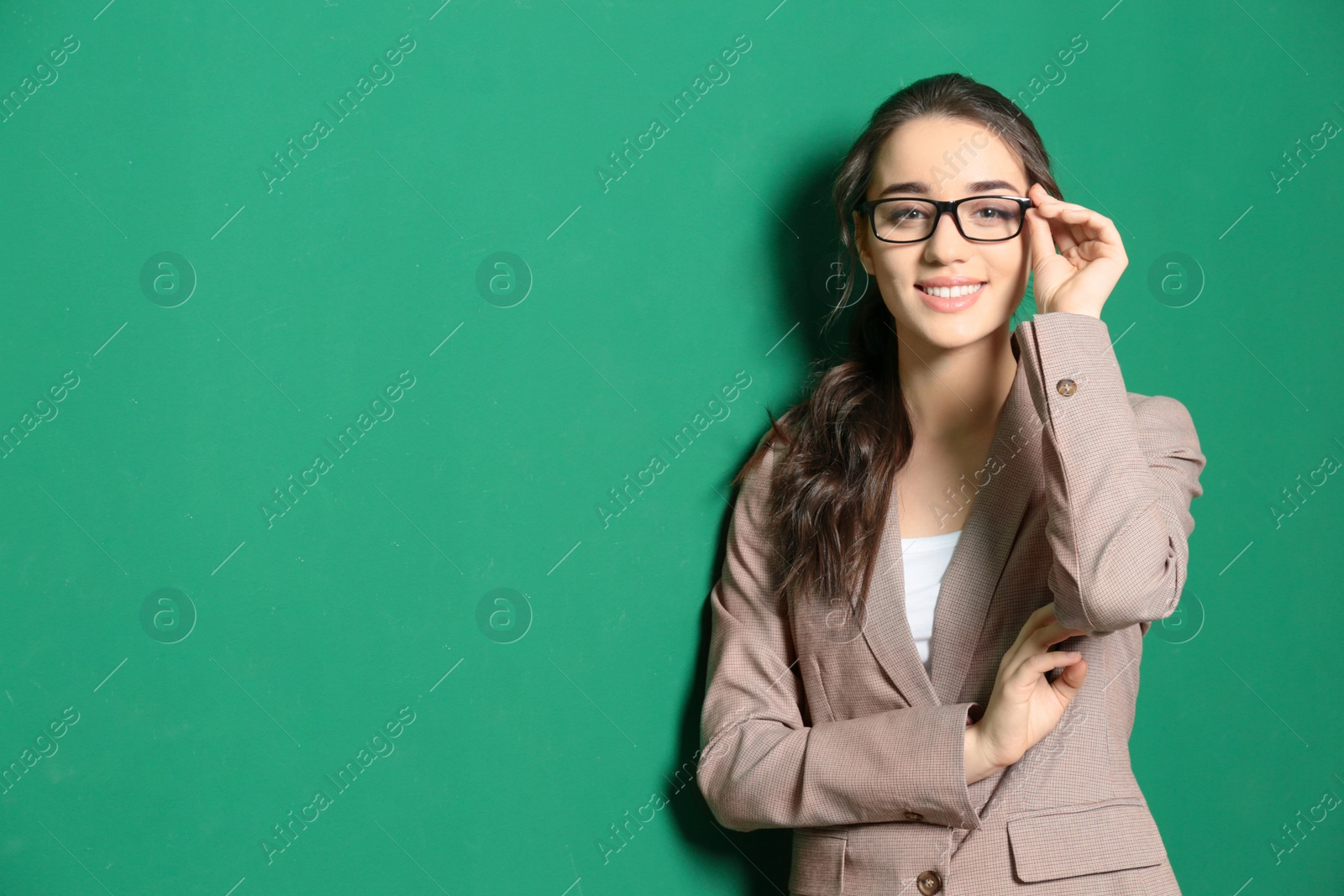 Photo of Portrait of beautiful young teacher near chalkboard, space for text