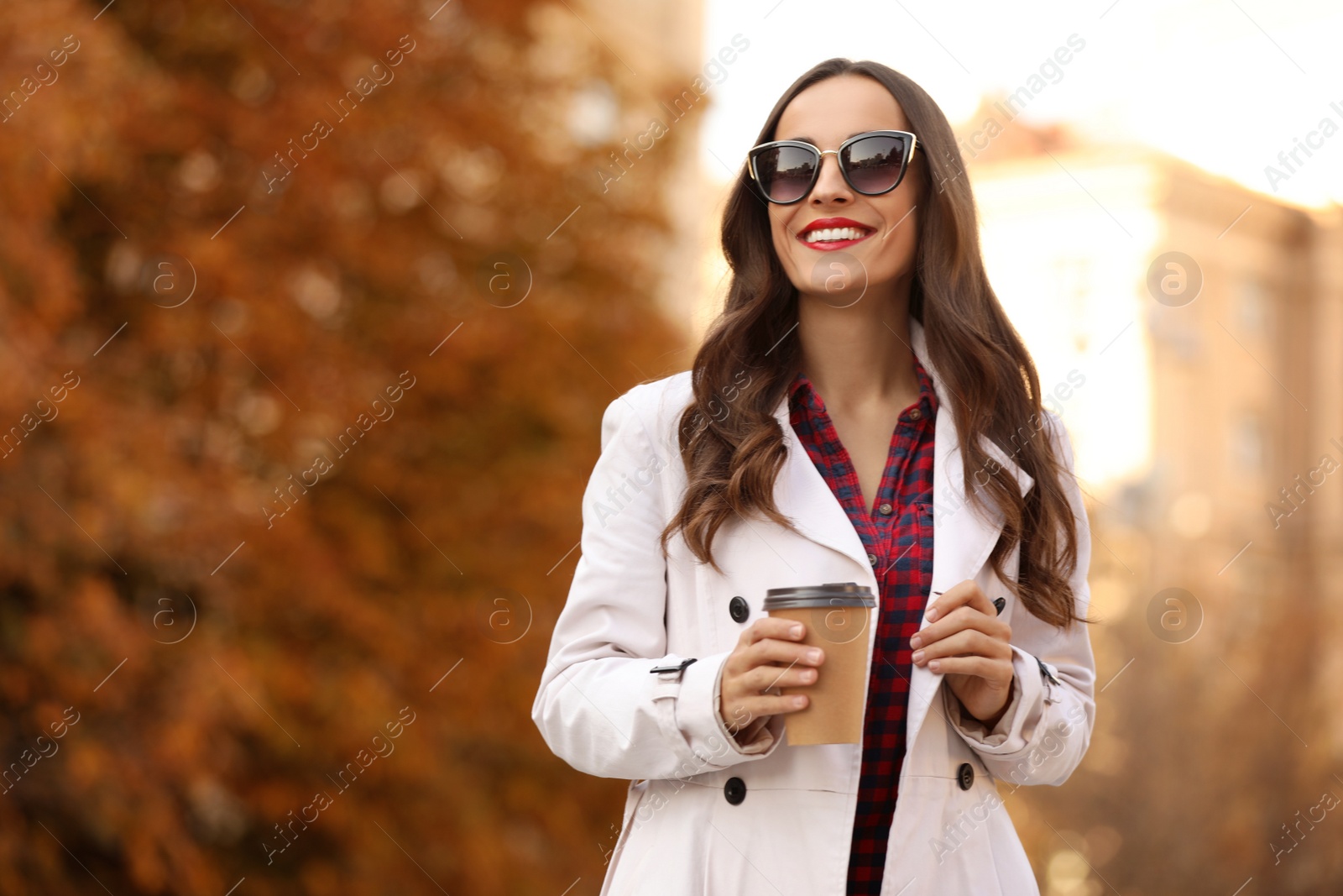 Photo of Beautiful woman with cup of coffee on city street. Autumn walk