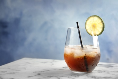 Photo of Glass of cocktail with cola, ice and cut lime on table. Space for text