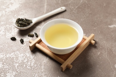 Cup of Tie Guan Yin oolong and spoon with tea leaves on table