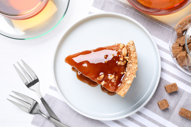 Photo of Slice of delicious cake with caramel sauce on table, flat lay