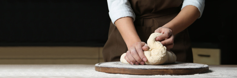 Image of Baker kneading dough at table, closeup with space for text. Banner design