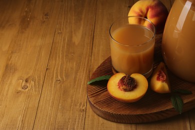 Delicious peach juice, fresh fruits and leaves on wooden table. Space for text