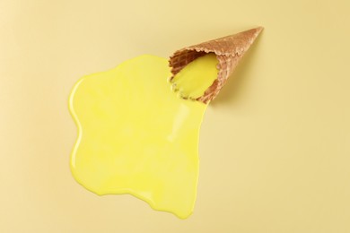 Photo of Melted ice cream and wafer cone on yellow background, above view