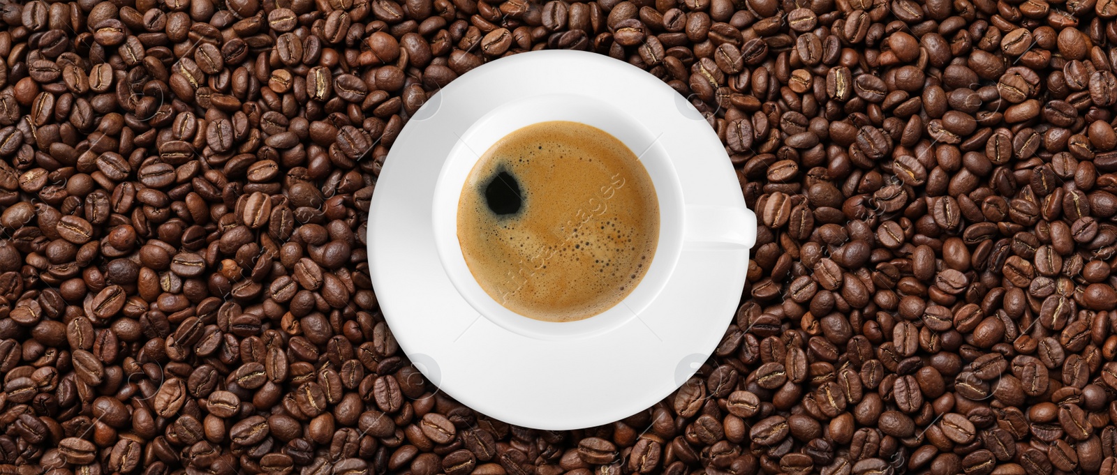 Image of Cup of tasty aromatic coffee on roasted beans, top view. Banner design