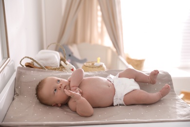 Photo of Cute little baby on changing table in room