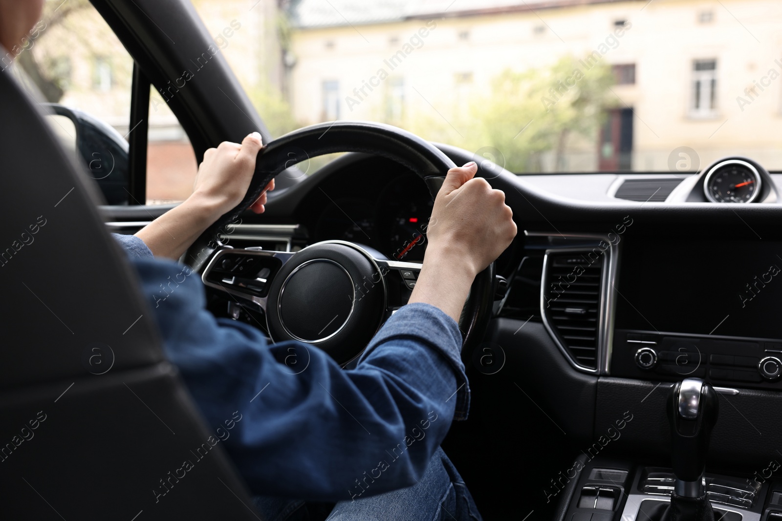 Photo of Woman holding steering wheel while driving her car, closeup