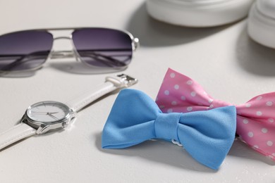 Photo of Stylish color bow ties, wristwatch and sunglasses on white background