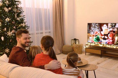 Photo of Happy family spending time together near TV in cosy room. Christmas atmosphere