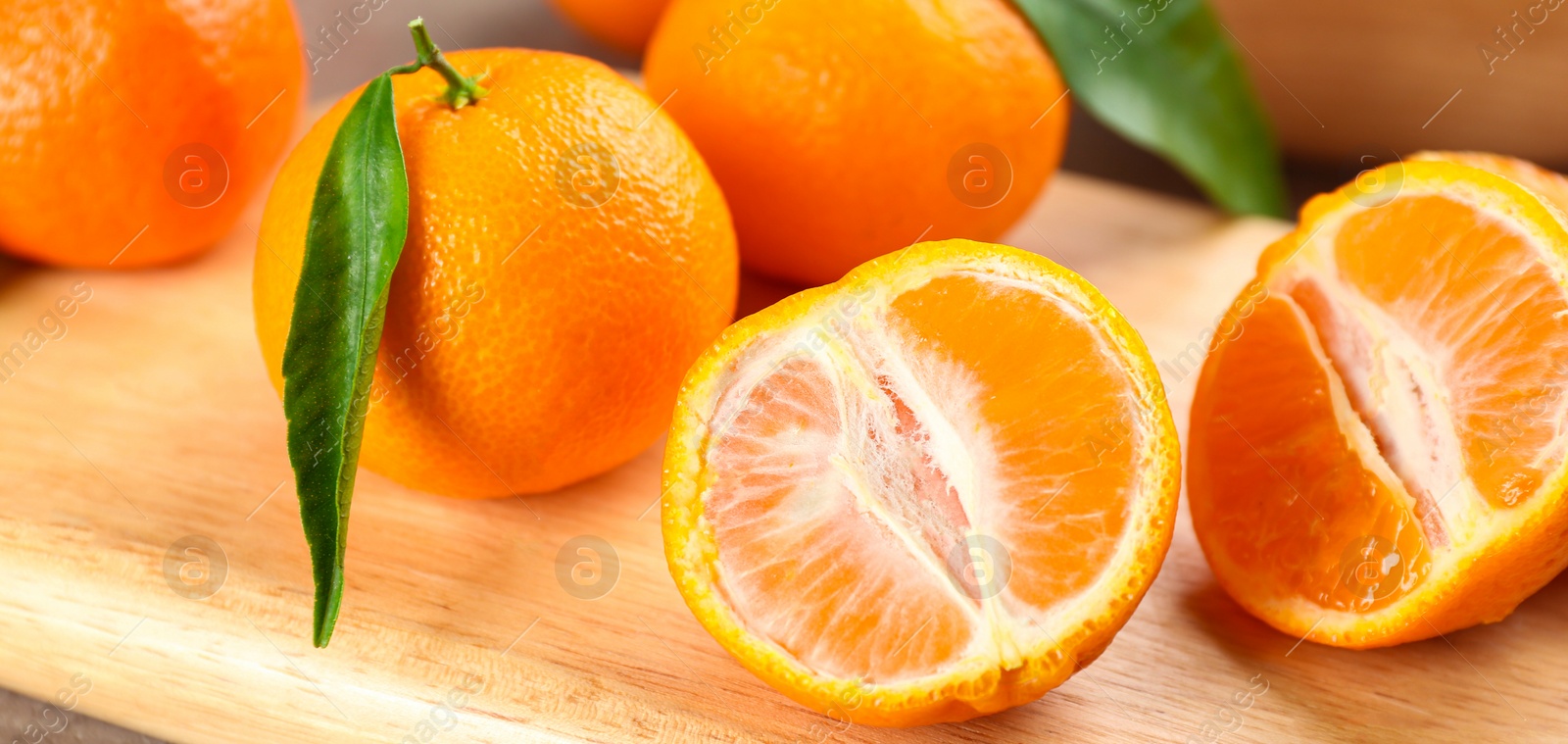 Photo of Delicious fresh tangerines on wooden board, closeup