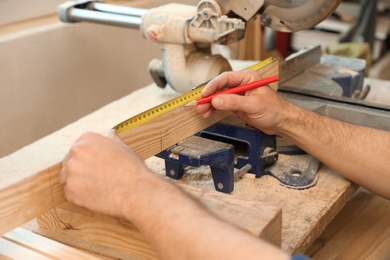 Working man measuring timber strip in carpentry shop, closeup