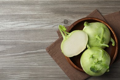 Photo of Whole and cut kohlrabi plants on wooden table, top view. Space for text