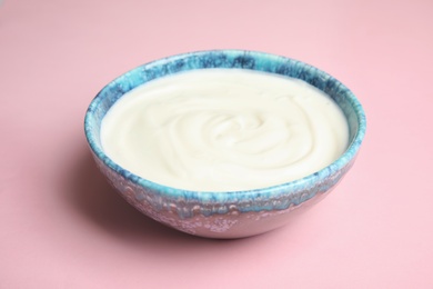 Bowl with creamy yogurt on color background