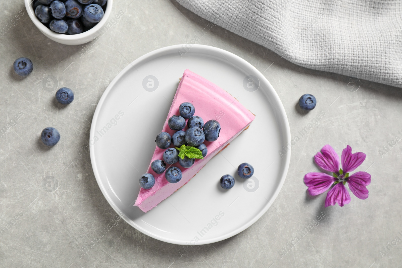 Photo of Plate with piece of tasty blueberry cake on light table, flat lay