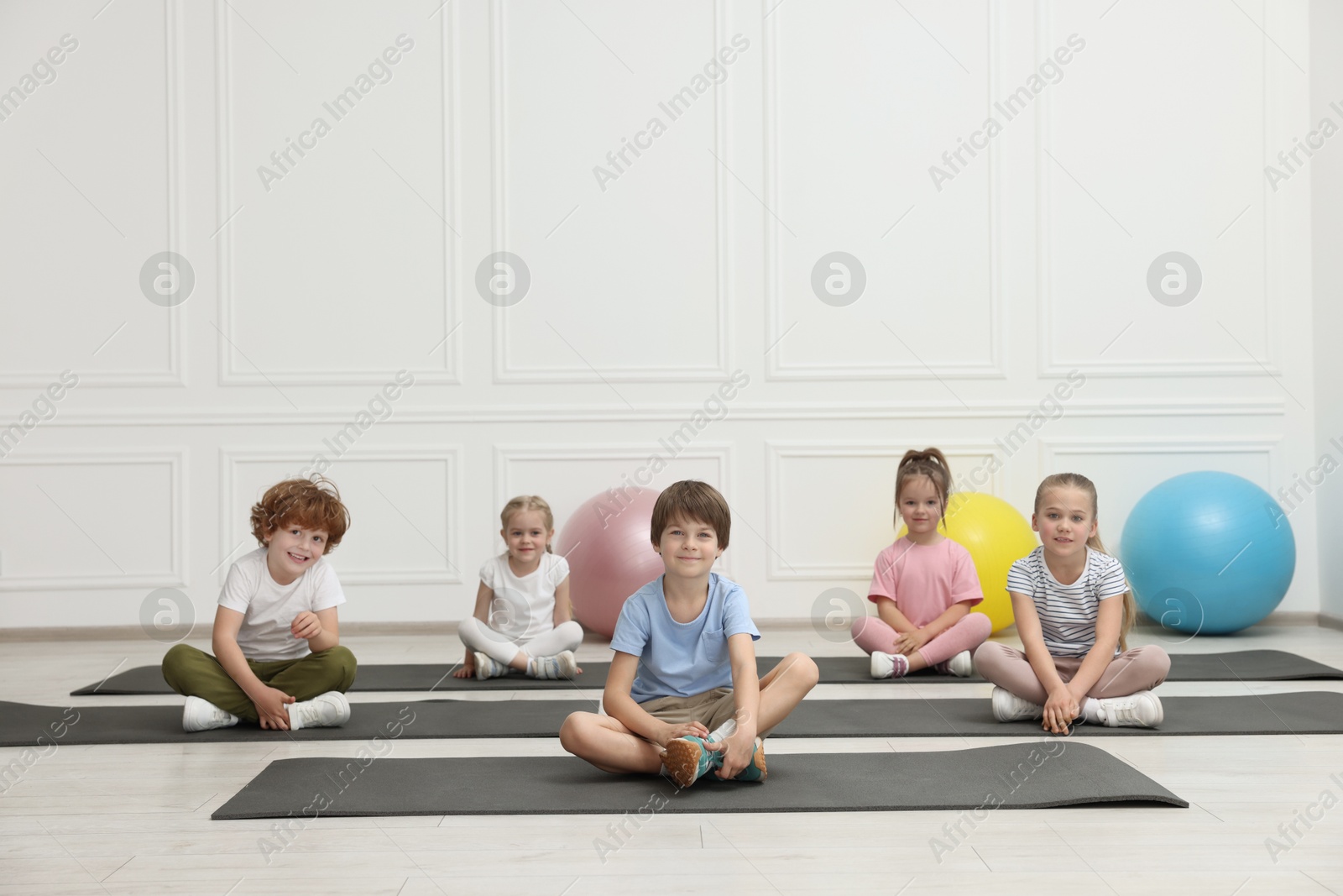 Photo of Group of children doing gymnastic exercises on mats indoors