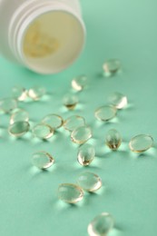 Bottle and vitamin capsules on turquoise background, closeup