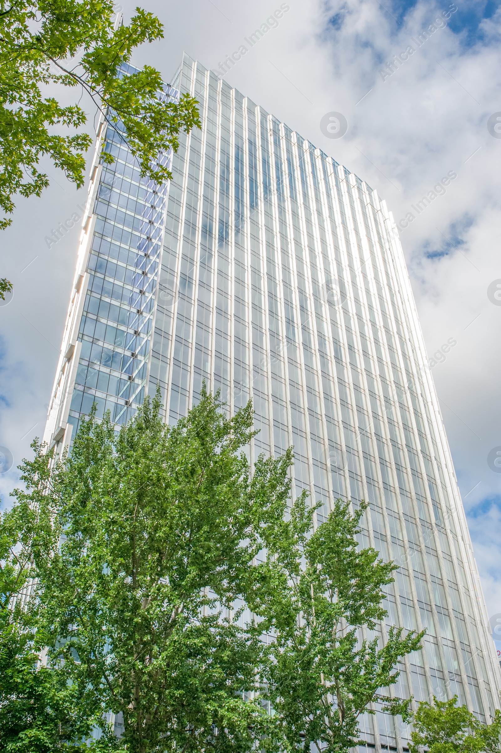 Photo of Beautiful skyscraper with many windows on cloudy day, low angle view