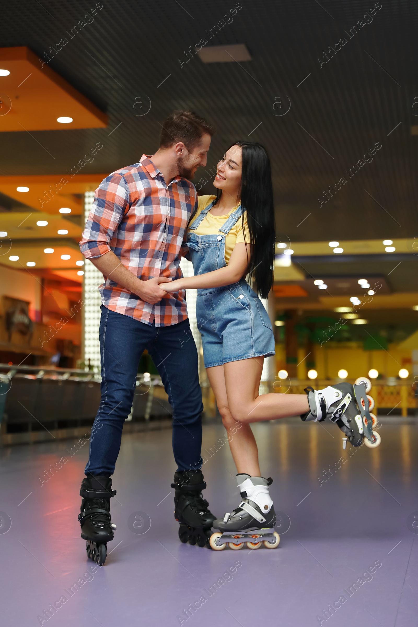 Photo of Young couple spending time at roller skating rink