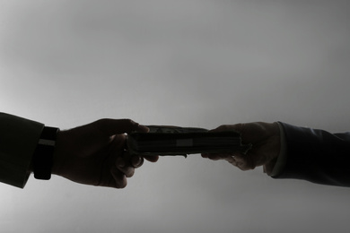 Silhouettes of woman giving bribe money to businessman on dark grey background, closeup