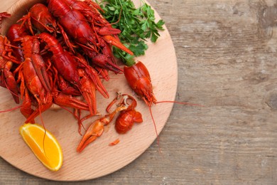 Photo of Delicious red boiled crayfish and orange on wooden table, top view