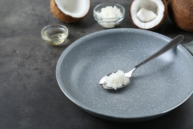 Photo of Frying pan with organic coconut cooking oil and spoon on grey table, space for text