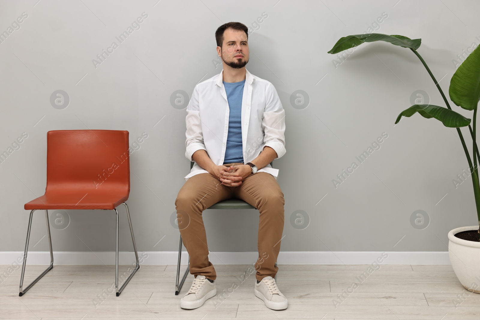 Photo of Man sitting on chair and waiting for appointment indoors